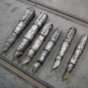 Sechs unterschiedlich lange silberne Füller liegen auf silbernem Untergrund